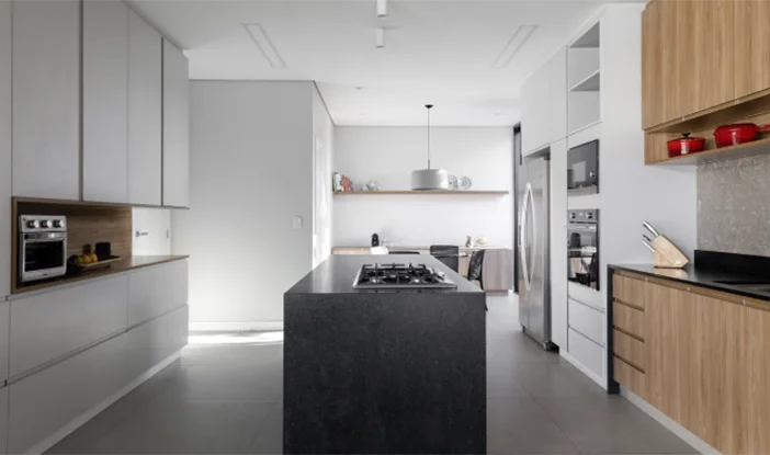 foto de uma cozinha, com ilha de granito preto ao centro e armários de madeira nas extremidades