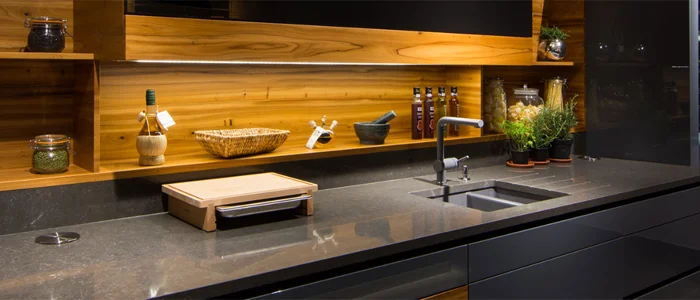Cozinha com armários pretos, revestimento amadeirado na parede e bancada de quartzo Crystal Anthracite