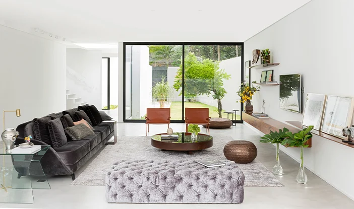 sala de estar de uma casa, com decoração minimalista e monocromática. De um lado, está o sofá. Do outro, as poltronas.