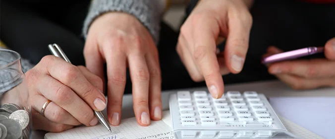 foto de mãos mexenod em celulares, calculadora, caneta e anotando no papel