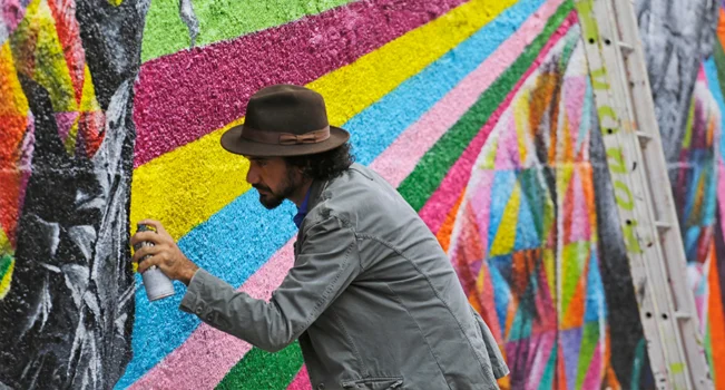foto do grafiteiro Eduardo Kobra pintando uma parede
