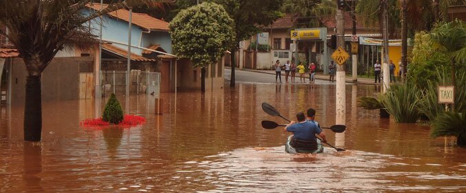 homem em canoa durante alagamento de cidade em minas gerais