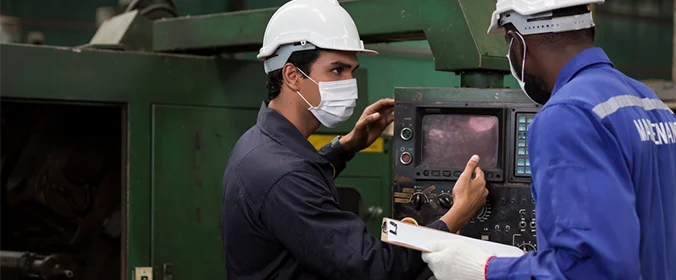 foto de dois funcionários conversando em frente a uma máquina