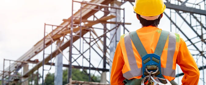pessoa com roupas de proteção de um canteiro de obras de costas para a câmera