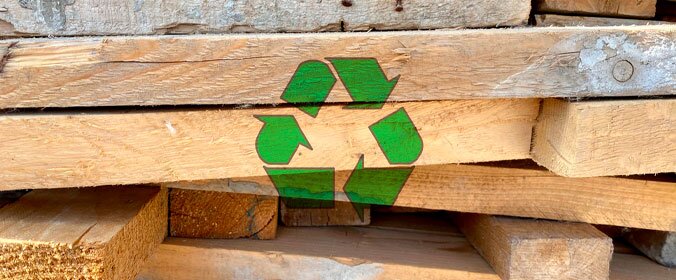 foto de várias madeiras empilhadas e um logo de reciclagem pintado sobre elas