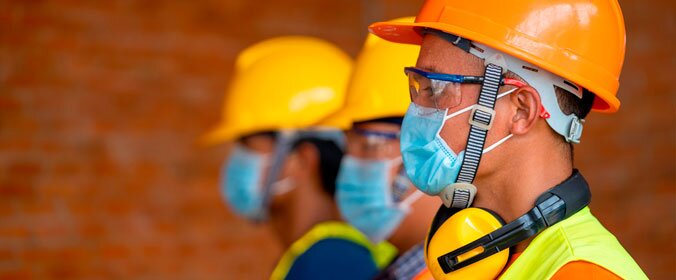 homem que trabalha em construção devidamente equipado e com máscara