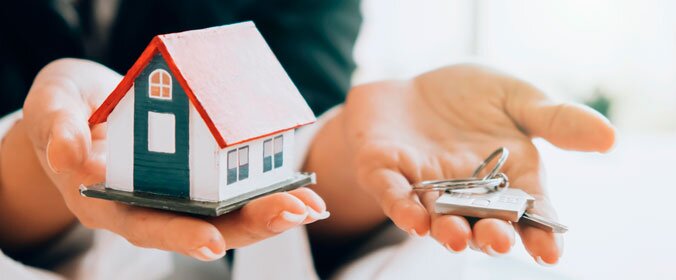imagem de uma mulher segurando uma casa em miniatura em uma mão e um molho de chaves em outra