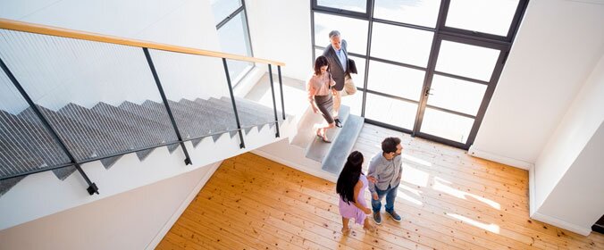 duas pessoas com dois corretores analisando uma casa na base de uma escada