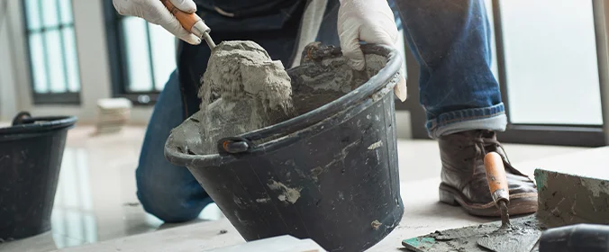 foto de um homem mexendo em um balde com cimento