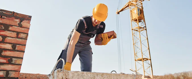 trabalhador da construção civil manipulando tijolos em um canteiro de obras