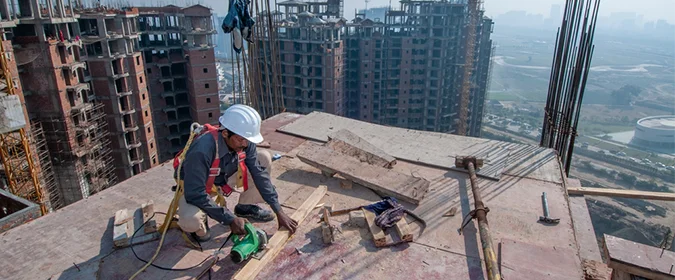 foto de um construtor trabalhando em um canteiro de obras no topo de um prédio