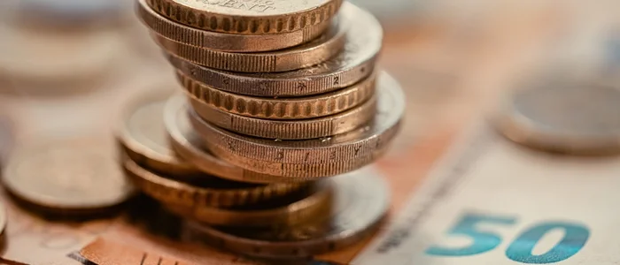 Moedas empilhadas sobre notas de dinheiro