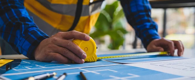foto de uma pessoa debruçada sobre uma mesa e com uma trena na mão