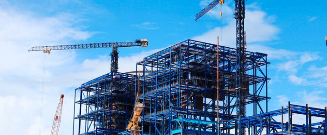 foto de uma grande construção em andamento, com equipamentos e andaimes em volta