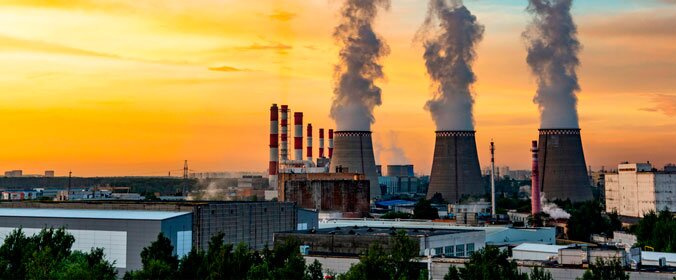 imagem de três chaminés de indústrias ao longe, indicando grande produção ativa