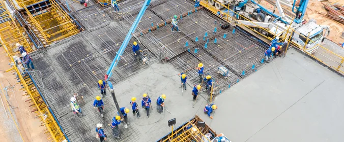 foto de uma série de trabalhadores da construção civil, devidamente equipados com os dispositios de segurança, em um canteiro de obras