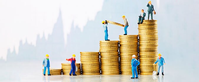 foto de varios montinhos de moeda, e bonecos trajados com equipamentos de construção sobre as pilhas