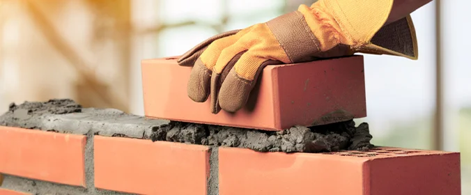 foto de uma pessoa colocando tijolos em uma parede