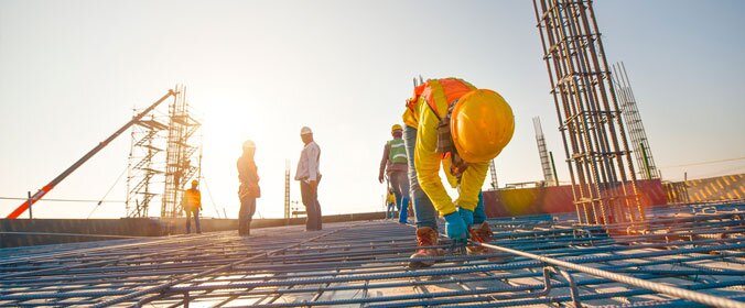 homem paramentado com equipamentos de segurança trabalhando em obra, com andaimes ao fundo