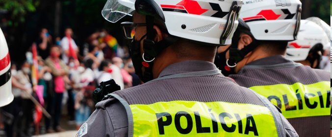 policiais fardados de costas com um colete fluorescente