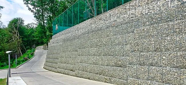 Na diferença de nível entre a rua e a casa o muro de arrimo com pedras
