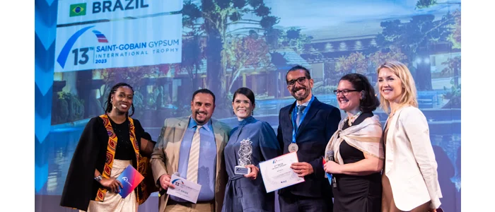 Apresentadores e vencedores do prêmio Gypsum Trophy sorrindo em um palco, com a imagem do Parque Aquamotion projetada atrás