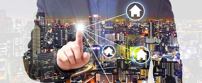 foto de uma pessoa clicando em uma tela, com hologramas de ícones de casas aparecendo e o fundo de uma cidade no fundo