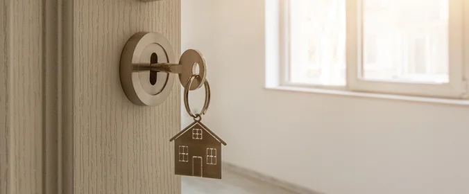 foto de uma chave na porta, com um chaveiro de casa