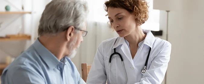 foto de uma pessoa caracterizada como médica e atendendo um senhor ao lado
