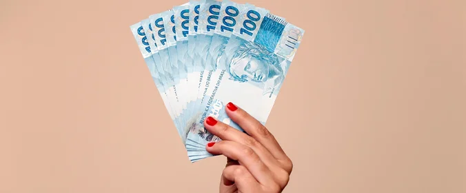 foto de uma mão segurando várias notas de 100 reais