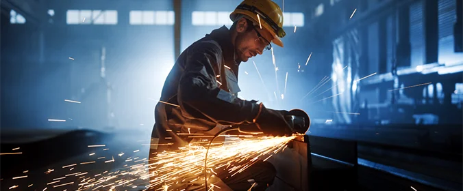 foto de um trabalhador soldando algo com o fundo escuro  
