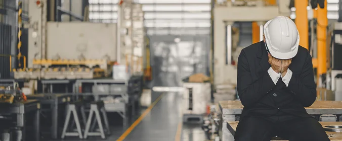 foto de um trabalhador sentado e cobrindo o rosto, denotando tristeza