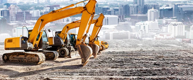 foto de três tratores, um ao lado do outro, em um canteiro de obras