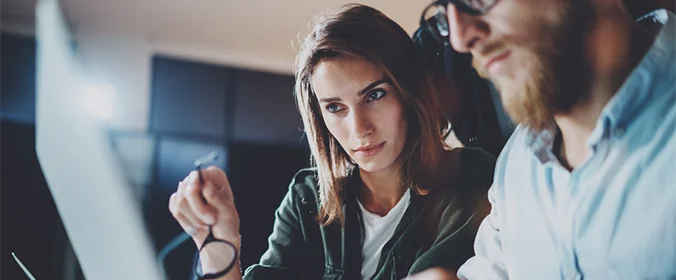 foto de duas pessoas olhando para a tela de um computador com cara de preocupadas