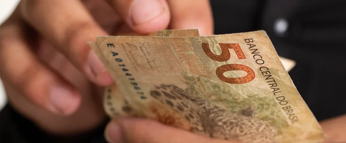 pessoa segurando notas de 50 reais