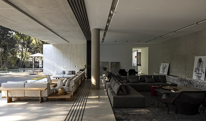Foto da área gourmet e sala de estar da Residência MC, onde sofás brancos e cinzas estão de costas um para o outro
