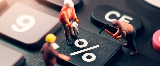 foto de três bonequinhos que simulam uma constução, como se fossem trabalhadores, em cima de um teclado que evidencia a tecla de porcentagem