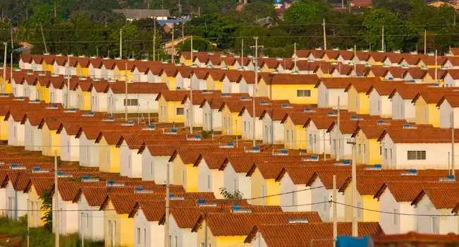 Vista panorâmica de um empreendimento do Minha Casa Minha Vida, que deve ser tendência na construção civil em 2025. As casas estão lado a lado e têm diferentes cores.