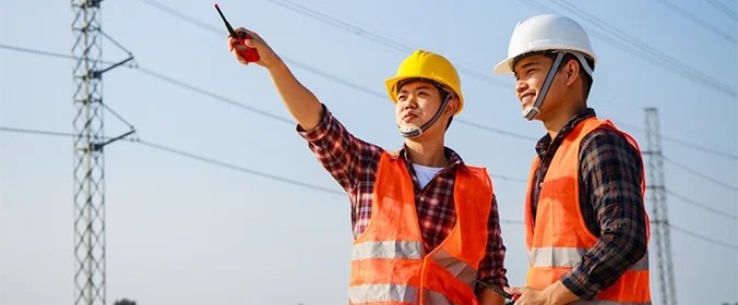 duas pessoas com equipamentos de segurança de canteiros de obra apontam para algum lugar