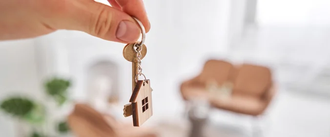 foto de uma mao segurando chaves com o chaveiro de uma casa